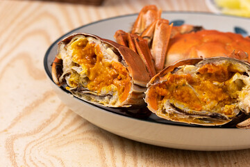 Close up of cooked crab meat and orange roe inside the shell