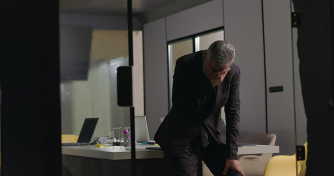 Corporate executive overwhelmed with emotion, covering face with hands during solitary moment in quiet office after meeting
