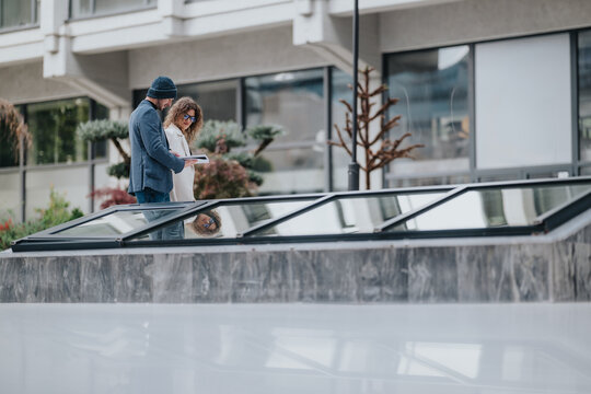 Two colleagues and friends discuss ideas outdoors by a modern glass skylight in a city setting, sharing a notebook and planning a project with calm, collaborative energy. - Powered by Adobe