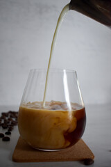 Preparing iced coffee, pouring cold milk