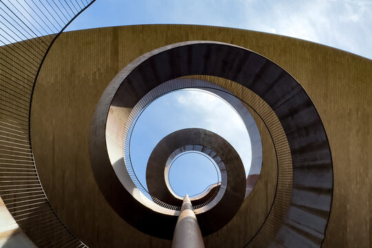 spiral staircase photographed from top view, capturing geometric curves, descending perspective and abstract architectural design