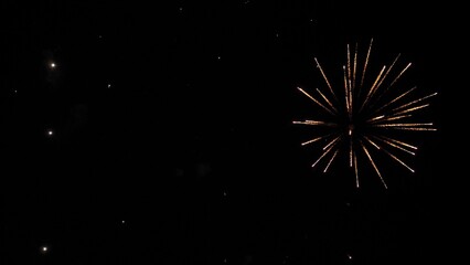 Firework explosions with glowing traces and stars in sky at nighttime holiday. Brilliant display of firework flashes illuminate black sky. Firework performance for spectators at evening party