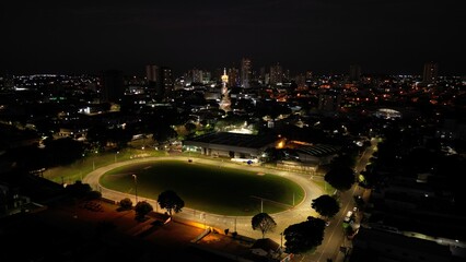 Aerial night view of an illuminated stadium with running track and city skyline. Sports, architecture, night. Perfect for sports, architecture, commercial themes.