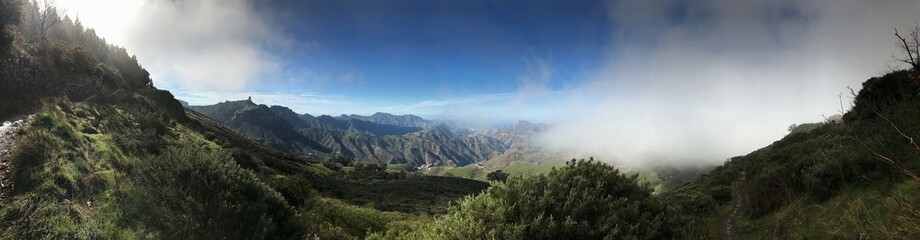 Naklejka premium Panoramic view of green valleys and mountains beneath a partly cloudy sky
