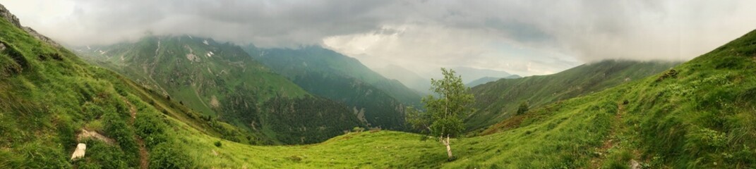 Lush green mountain landscape panorama with clouds and wilderness