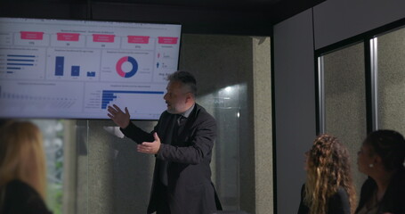 Confident business leader delivering passionate presentation to engaged colleagues during corporate...