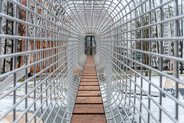 Climbing wall on the playground in the form of a metal mesh tunnel