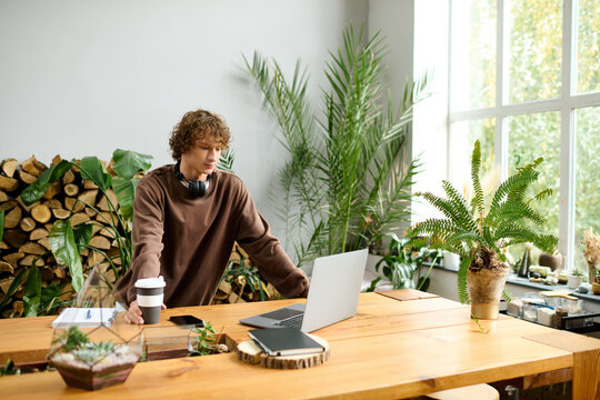 Creative young man working in a bright, nature inspired workspace with plants and wooden decor