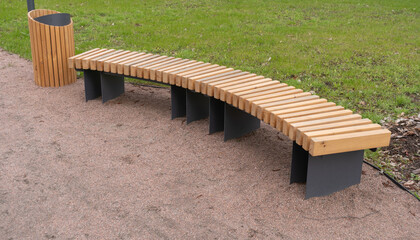 Empty wooden bench and trash can in city park. Concept of recreation, tanning