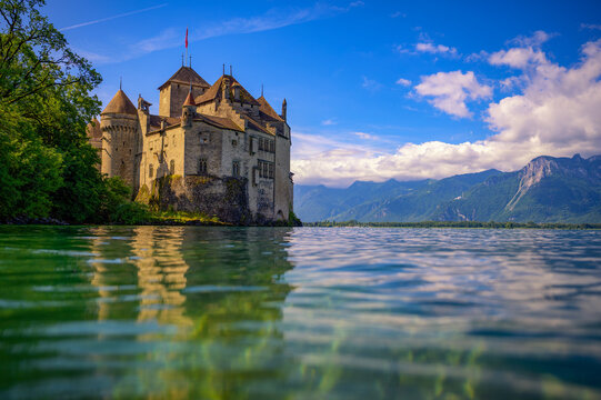 Montreux, Switzerland - July 2, 2024 : Historic Chillon Castle on the shore of Lake Geneva with Swiss Alps in the background, near Montreux, Switzerland.