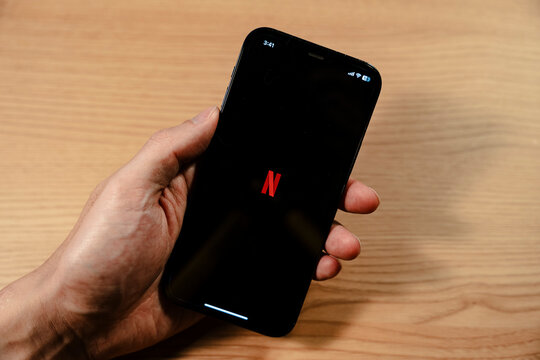 Hand holding smartphone showing NETFLIX app splash screen - Seoul, South Korea - November 23 2025