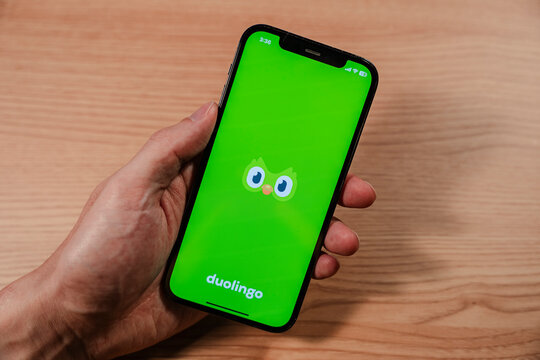 Hand holding smartphone displaying DUOLINGO splash screen - Seoul, South Korea - November 23 2025