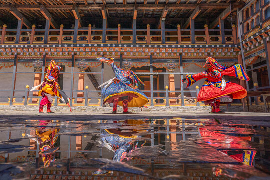 Jakar, Bhutan - 24 September 2025: View of dancers in vibrant traditional attire reflected in a rain-slicked courtyard, evoking the rich cultural heritage and spiritual energy of the sacred space.