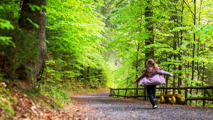 Young girl running on a dirt road in a green forest