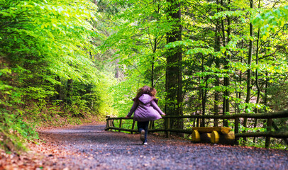 Young girl running on a dirt road in a green forest