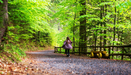 Young girl running on a dirt road in a green forest