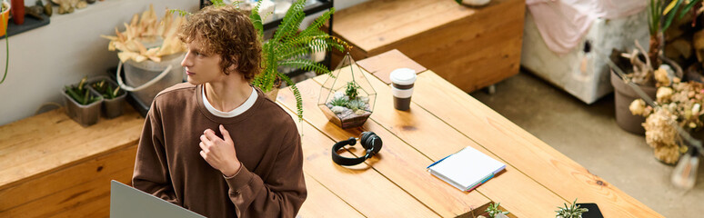 Young creative man thinking in a bright workspace surrounded by plants and welcoming decor