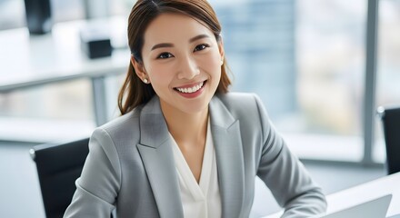 Asian professional with a warm smile in an office setting, radiating positivity and confidence.
