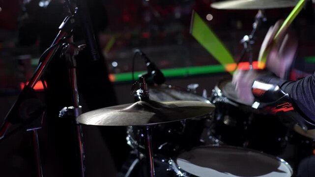 Energetic drummer crafts beating sequences radiating vivid excitement. Echoing pulses roll through dark arena amplifying crowd response
