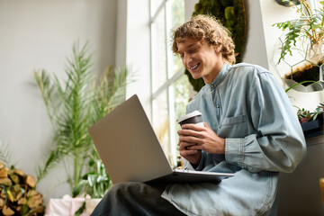 Creative young man enjoying coffee while working on laptop in a cozy, artistic environment
