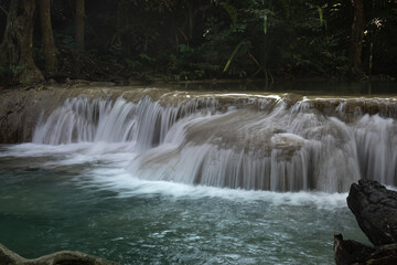 Obraz premium Waterfall forest stream cascade rock moss tropical serene clear nature flows over layered rock tranquil forest scene, soft mist rising, gentle motion, calming mood, lush foliage framing turquoise