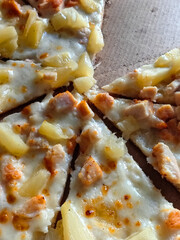 Savory slice of pizza topped with chicken and pineapple on wooden surface