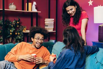 Young diverse friends enjoying a home party, laughing and conversing on a sofa