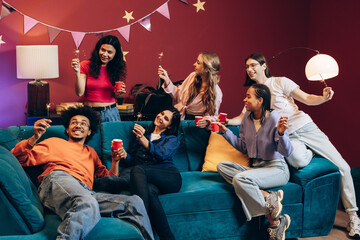 Young diverse friends enjoying a home party with sparklers and drinks