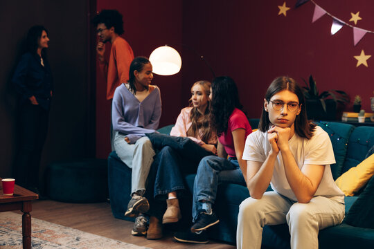 Young man feeling left out and isolated during a social gathering with friends