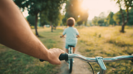 Obraz premium Father following young son riding bicycle in sunny park pov