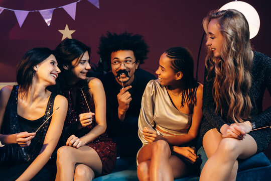 Diverse friends having fun at a party, celebrating with photobooth props