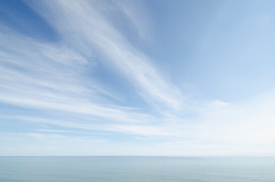 White wispy clouds above calm sea