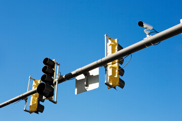 Traffic camera on traffic signal post against clear sky