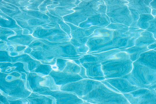 Light blue water reflecting sunlight in swimming pool