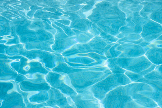 Light blue water reflecting sunlight in swimming pool