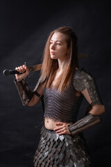 Obraz premium Portrait of a young woman, fantasy warrior in armor with a sword in her hands isolated on a dark background.