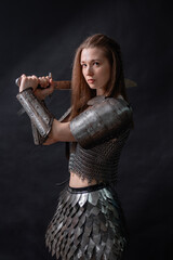 Obraz premium Portrait of a young woman, fantasy warrior in armor with a sword in her hands isolated on a dark background.