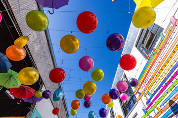 Low angle view of colorful balloons hanging between buildings