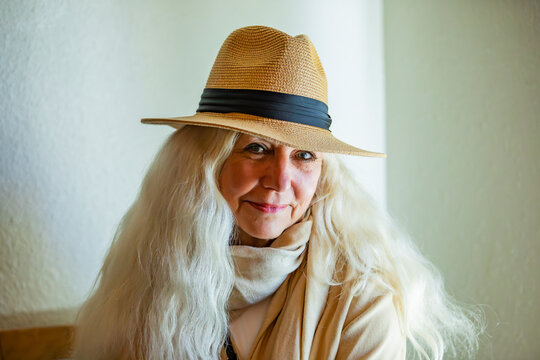 Portrait of smiling woman with white long hair and fedora hat