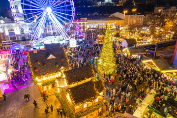 Aerial drone view of a festive Christmas market with a Ferris wheel at night.