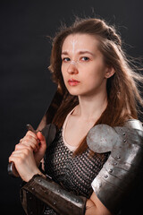 Obraz premium Portrait of a young woman, fantasy warrior in armor with a sword in her hands isolated on a dark background.