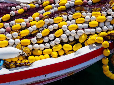 Pile of fishing nets with yellow and white buoys on boat