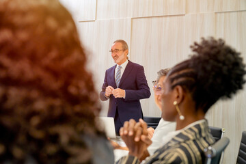 Focusing on Businessman manager stand on head of meeting table in meeting room for lead the business meeting with diverse team.