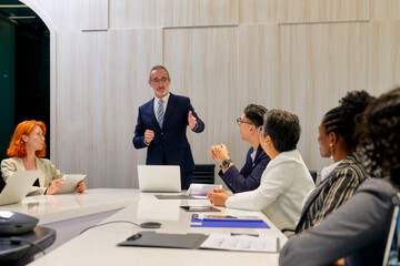 Businessman boss stand on the head of table lead the meeting and present agenda subject in meeting room for marketing plan.