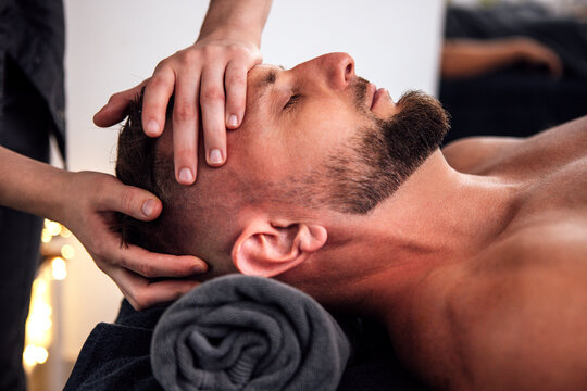Male client receiving a relaxing head massage in a serene spa environment, with soft lighting and towels, promoting wellness and relaxation techniques for stress relief