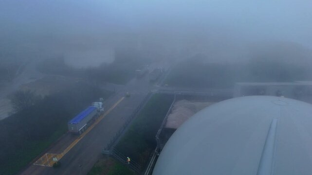 Aerial drone view of industrial factory domes, biogas generation production plant in foggy conditions with smoke stacks, Bury Saint Edmunds, UK