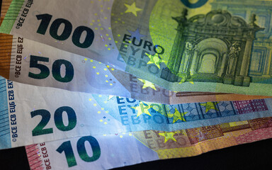 european euro banknotes under UV light, revealing advanced security features and anti-counterfeiting elements. financial banking and economy concept
