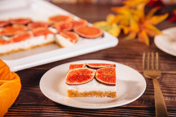 A delicious slice of fig and cream cheesecake on a white plate, topped with fresh fig slices