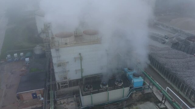 Aerial drone view of industrial turbine cooling fans, smoke plumes and vapour in foggy conditions, Bury Saint Edmunds, UK