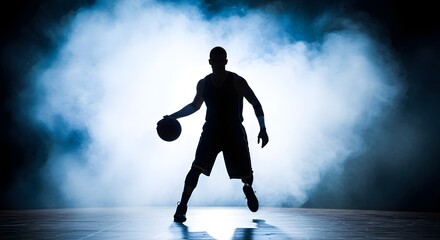 Silhouette of basketball player dribbling ball against a smoky blue background in a studio